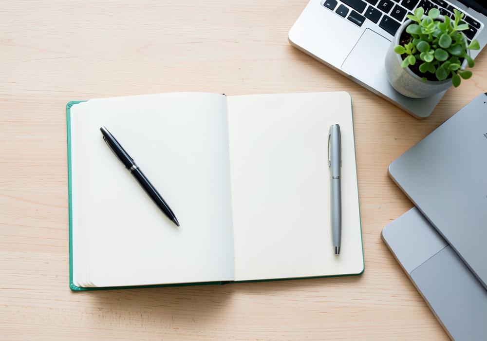 A notebook and laptop on a desk